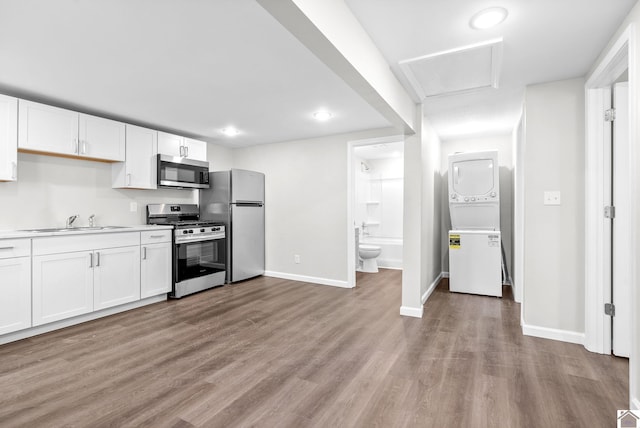 kitchen with white cabinets, stacked washing maching and dryer, sink, and appliances with stainless steel finishes