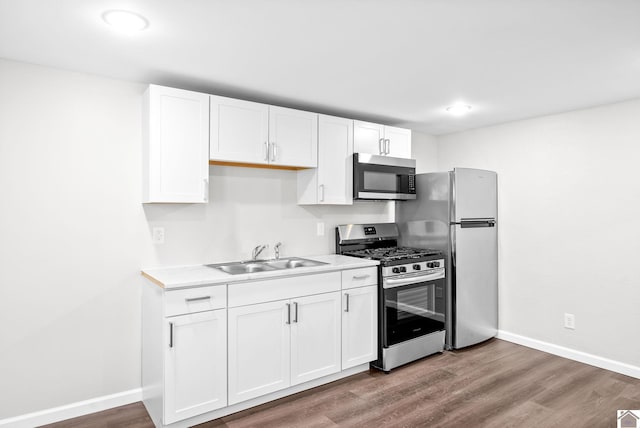 kitchen featuring white cabinetry, sink, stainless steel appliances, and hardwood / wood-style flooring