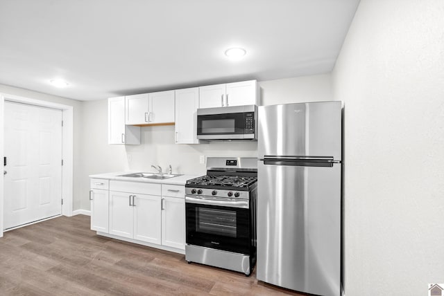 kitchen featuring white cabinets, stainless steel appliances, light hardwood / wood-style floors, and sink