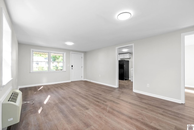 empty room featuring dark hardwood / wood-style flooring and an AC wall unit