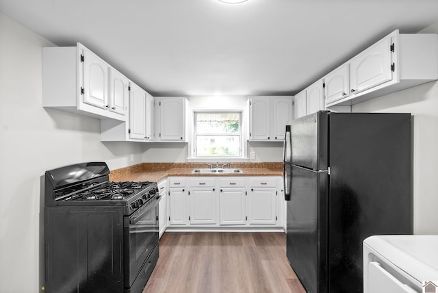 kitchen with black appliances, white cabinets, sink, light hardwood / wood-style floors, and washer / clothes dryer