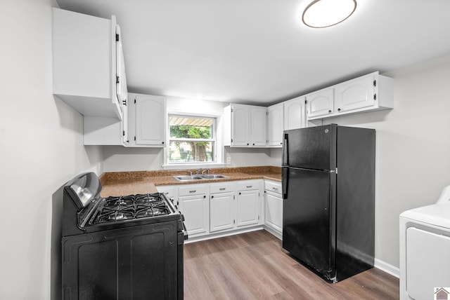 kitchen featuring black appliances, white cabinets, sink, light wood-type flooring, and washer / clothes dryer