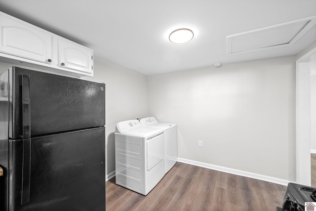 clothes washing area with dark hardwood / wood-style flooring, washer and clothes dryer, and cabinets