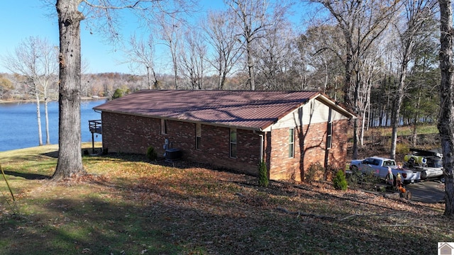 view of side of property with central AC unit, a water view, and a yard