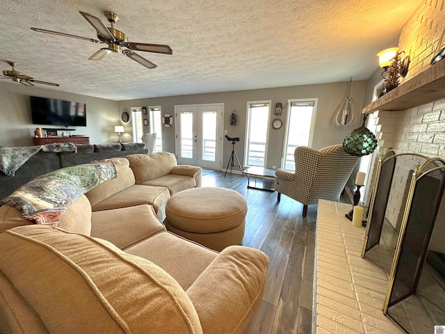 living room with french doors, light wood-type flooring, a textured ceiling, ceiling fan, and a fireplace