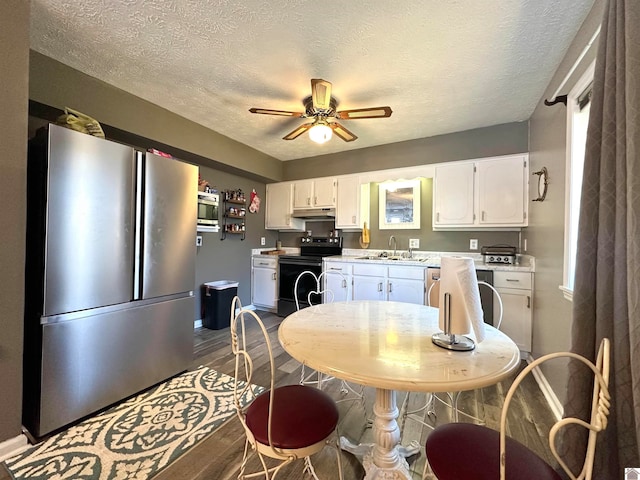 kitchen featuring sink, appliances with stainless steel finishes, a textured ceiling, white cabinets, and hardwood / wood-style flooring