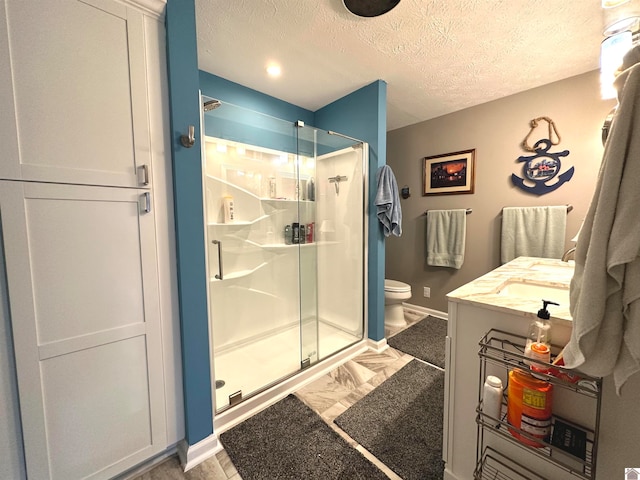 bathroom with vanity, toilet, a shower with shower door, and a textured ceiling