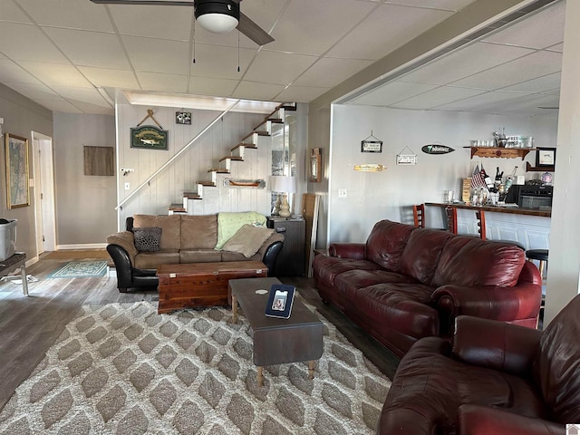 living room featuring hardwood / wood-style flooring, ceiling fan, and a drop ceiling