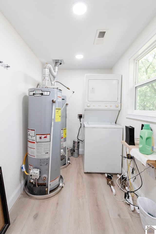 laundry room with light hardwood / wood-style flooring, stacked washer and clothes dryer, and water heater