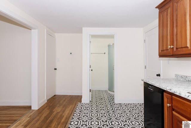 kitchen featuring hardwood / wood-style floors, light stone counters, and black dishwasher