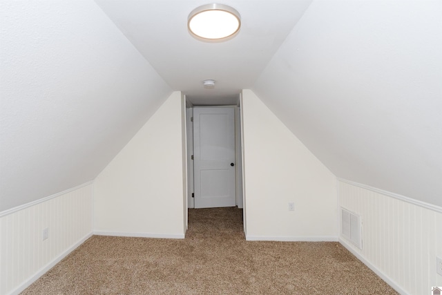 bonus room with light colored carpet and vaulted ceiling