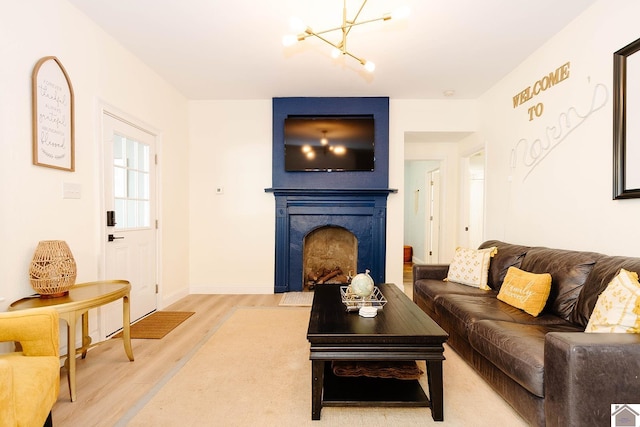 living room with wood-type flooring, a fireplace, and a chandelier