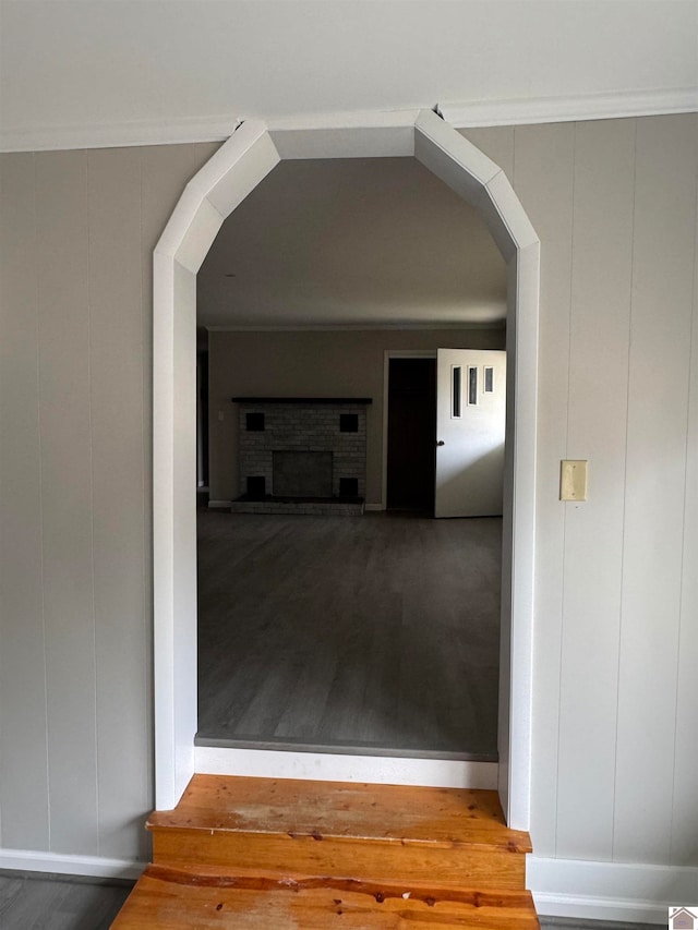 hallway with wood-type flooring, crown molding, and wood walls