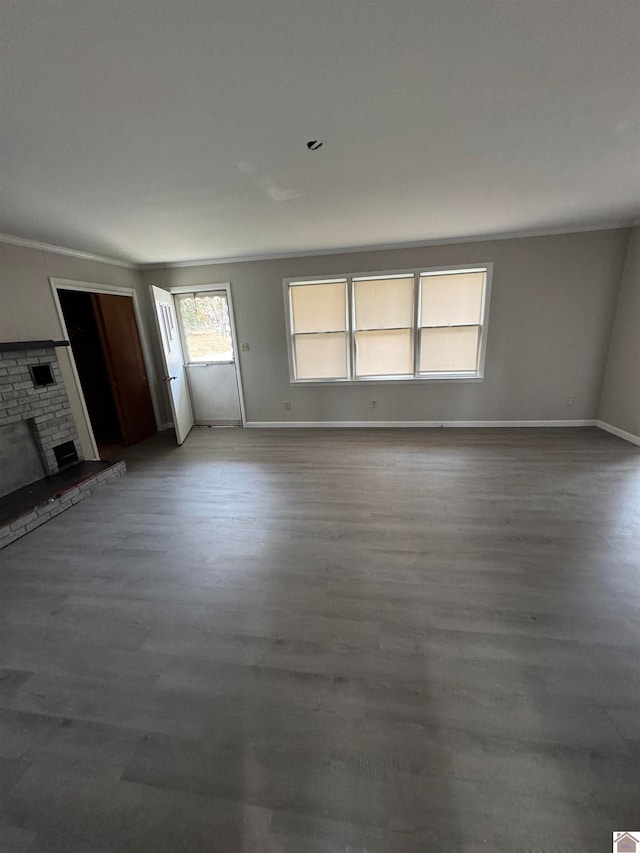 unfurnished living room with hardwood / wood-style flooring, crown molding, and a brick fireplace