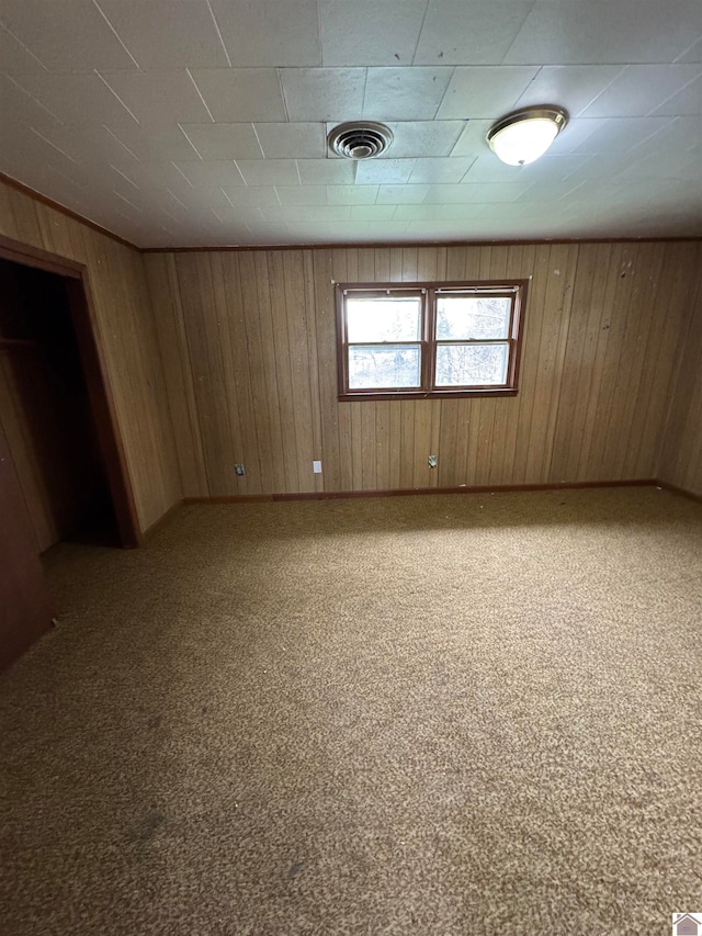 carpeted empty room featuring wooden walls