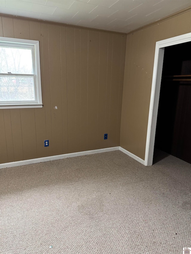 unfurnished bedroom with carpet floors and wooden walls