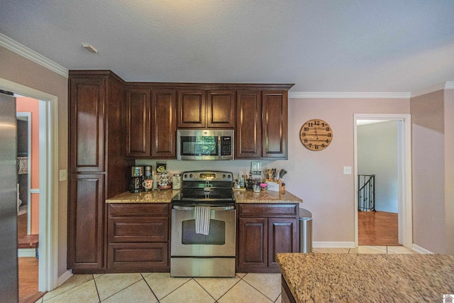 kitchen with light tile patterned flooring, ornamental molding, a textured ceiling, and appliances with stainless steel finishes