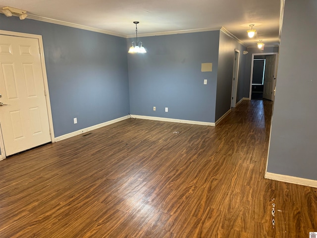 unfurnished room featuring dark hardwood / wood-style flooring, crown molding, and a notable chandelier