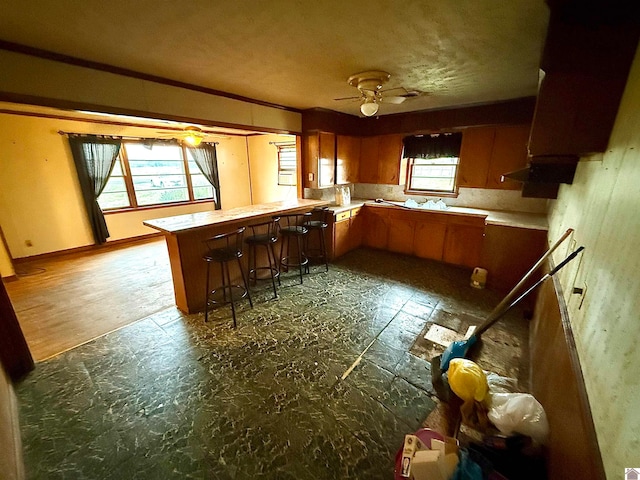 kitchen featuring a breakfast bar area, kitchen peninsula, ceiling fan, and dark hardwood / wood-style flooring