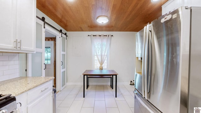 kitchen with decorative backsplash, stainless steel refrigerator with ice dispenser, light stone countertops, a barn door, and white cabinetry