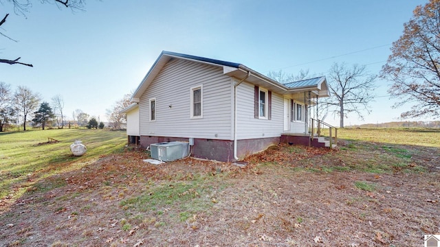 view of side of property featuring a lawn and central AC