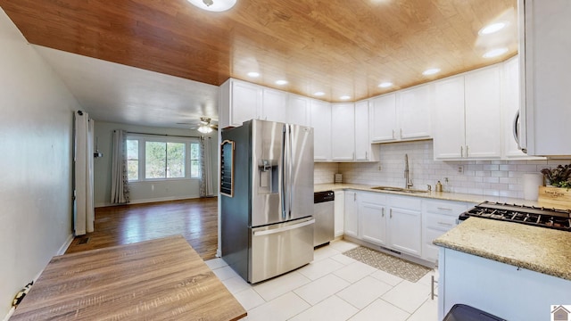 kitchen featuring white cabinetry, sink, light stone counters, light hardwood / wood-style floors, and appliances with stainless steel finishes