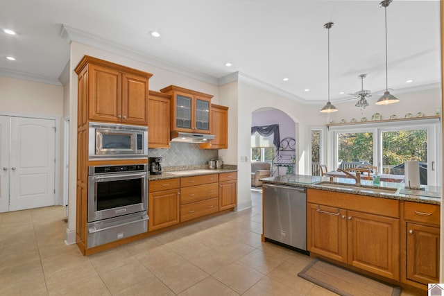 kitchen with pendant lighting, sink, ceiling fan, light stone countertops, and appliances with stainless steel finishes