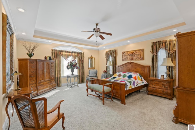 carpeted bedroom with a tray ceiling and ceiling fan