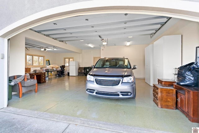 garage featuring ceiling fan, a garage door opener, and white refrigerator