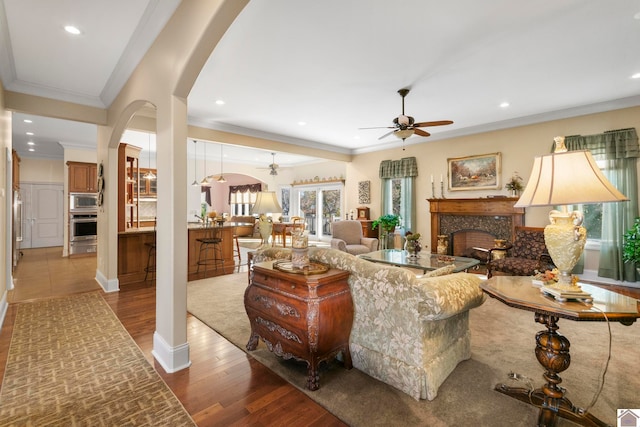 living room featuring ceiling fan, wood-type flooring, and ornamental molding