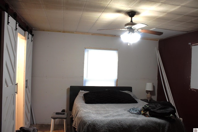 bedroom with ceiling fan and a barn door