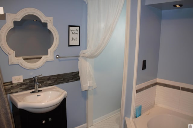 bathroom featuring vanity, decorative backsplash, and a bath