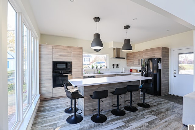 kitchen featuring a wealth of natural light, pendant lighting, black appliances, and sink