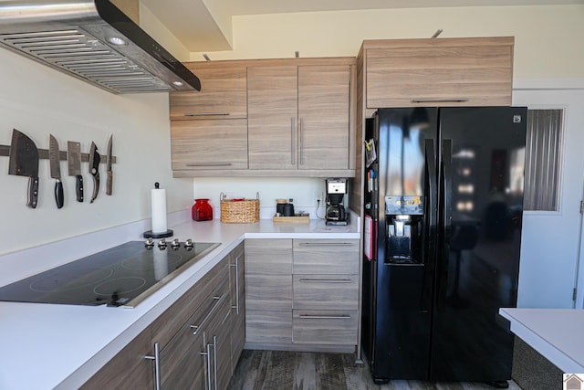 kitchen with black appliances, wall chimney exhaust hood, and dark wood-type flooring