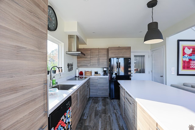 kitchen with dark hardwood / wood-style flooring, wall chimney exhaust hood, sink, black appliances, and hanging light fixtures