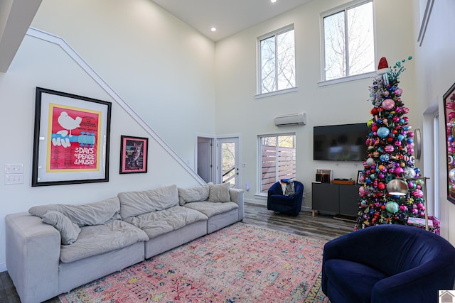 living room with a high ceiling, an AC wall unit, and wood-type flooring