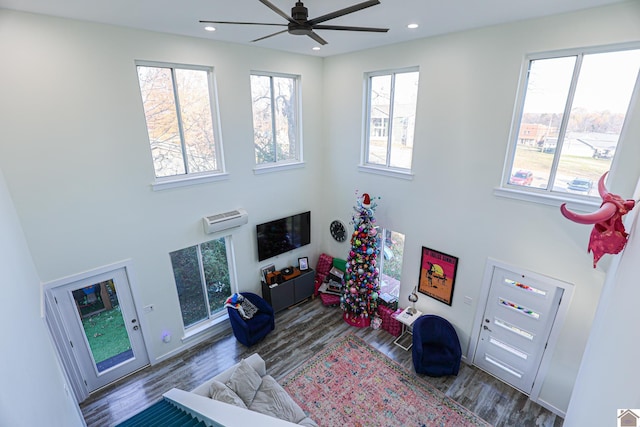 living room featuring a wall mounted AC, hardwood / wood-style floors, and ceiling fan