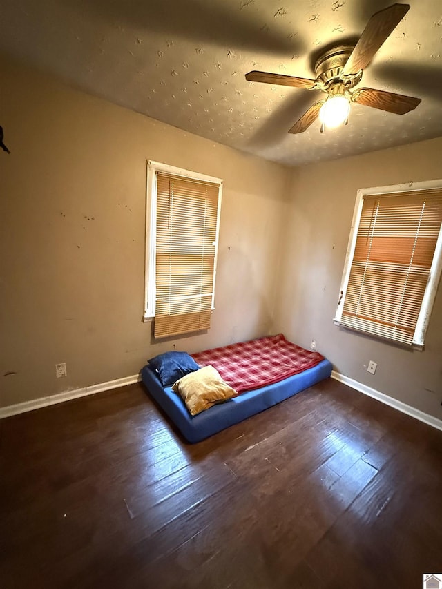 unfurnished bedroom with ceiling fan and dark wood-type flooring