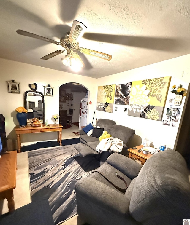 carpeted living room featuring ceiling fan and a textured ceiling