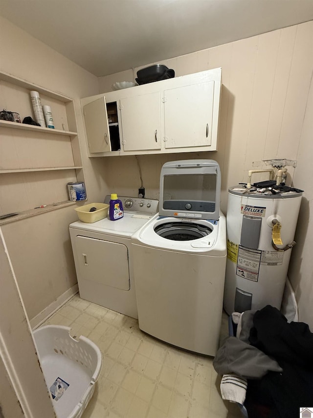 washroom with cabinets, washing machine and dryer, and water heater