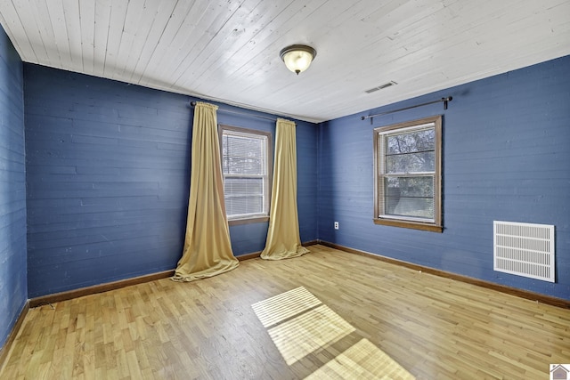 empty room with light wood-type flooring, a wealth of natural light, and wooden ceiling