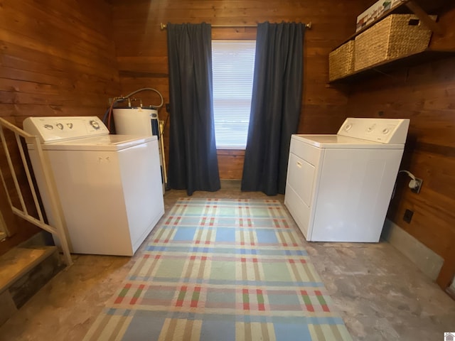 laundry room featuring separate washer and dryer, wooden walls, and electric water heater