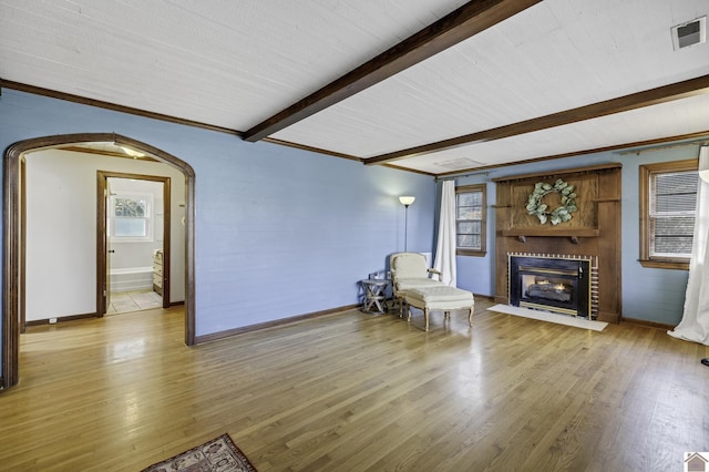 living area with beamed ceiling, crown molding, and light hardwood / wood-style floors