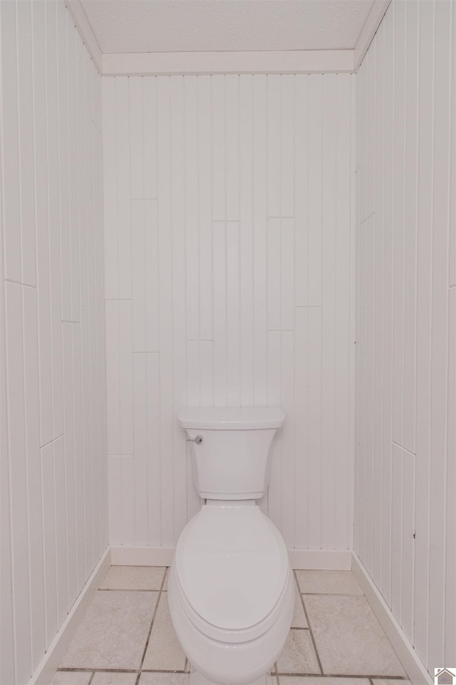 bathroom with tile patterned floors, toilet, and wood walls