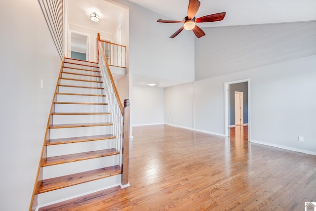 stairs featuring ceiling fan, wood-type flooring, and a high ceiling