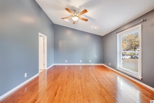 unfurnished room with ceiling fan, light wood-type flooring, a textured ceiling, and vaulted ceiling