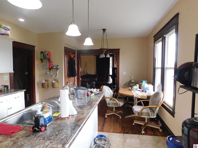 kitchen featuring white cabinetry, light hardwood / wood-style flooring, dark stone counters, and decorative light fixtures