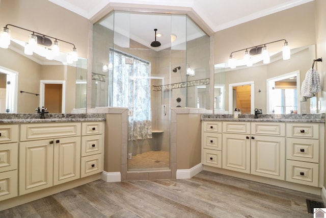 bathroom with wood-type flooring, vanity, a shower with door, and crown molding