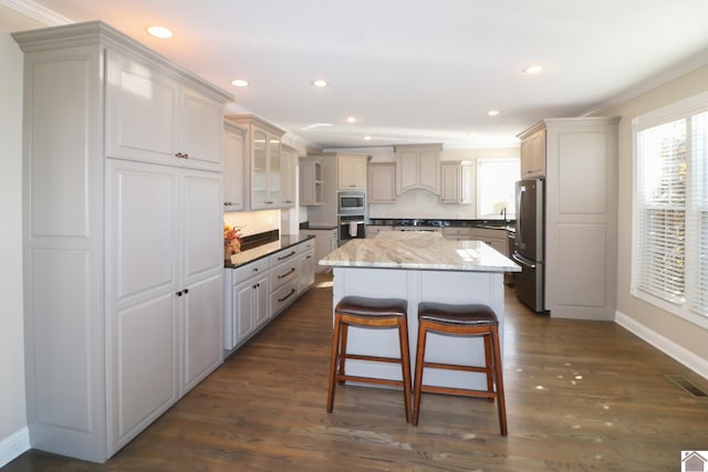 kitchen featuring a kitchen island, ornamental molding, dark wood-type flooring, and appliances with stainless steel finishes