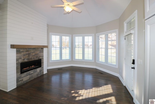 unfurnished living room featuring a stone fireplace, ceiling fan, and dark hardwood / wood-style floors